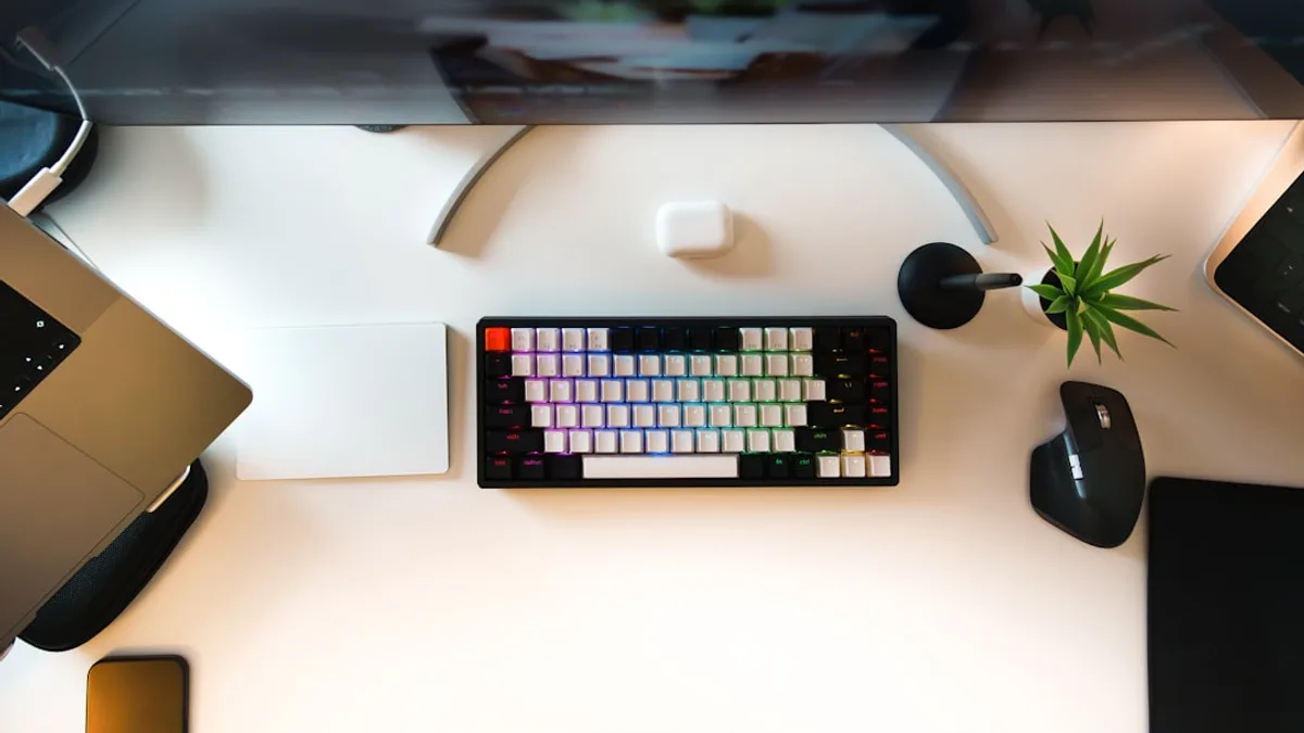 A desk with a laptop, keyboard, mouse and a plant