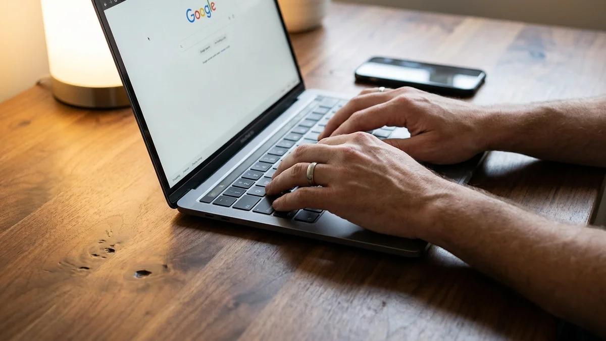 Hands typing a Google AI agent prompt on a MacBook keyboard