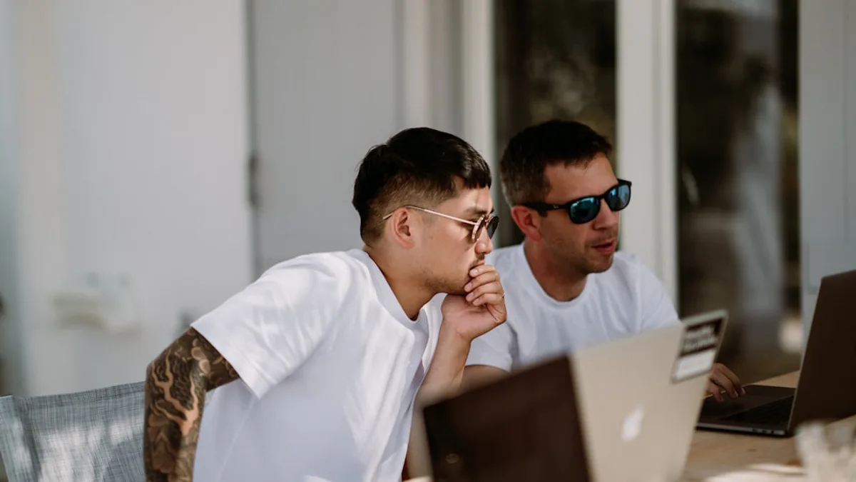 two men sitting on chairs while using laptop computers